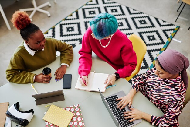 A team of content creators collaborating around a table, using AI tools on their laptops to brainstorm ideas and generate content, emphasizing the teamwork aspect.